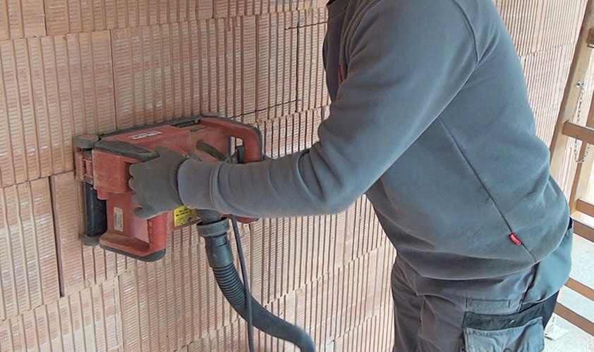 Handwerker fräst mit einer Mauernutfräse einen Wandschlitz in eine Betonwand